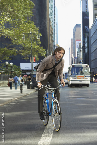 Portrait of handsome young businessman riding bicycle on urban street