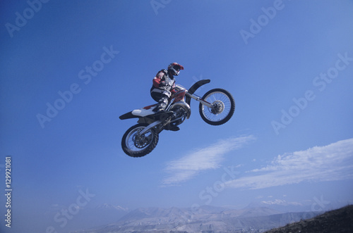 Low angle view of a man on mountain bike jumping against blue sky