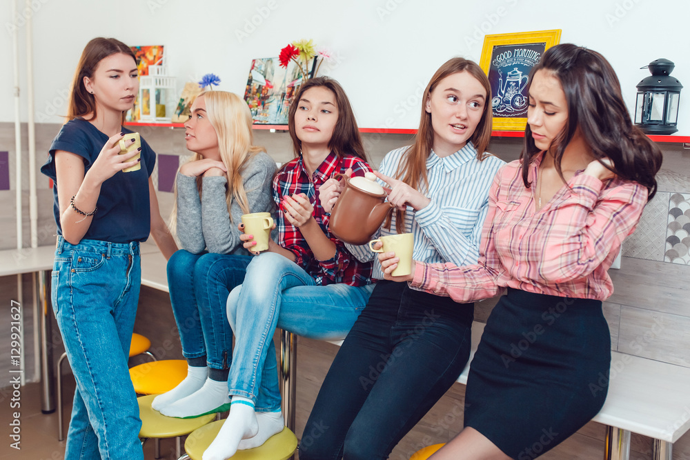 Obraz premium Beautiful girls standing in kitchen at the hostel talking and drinking tea.