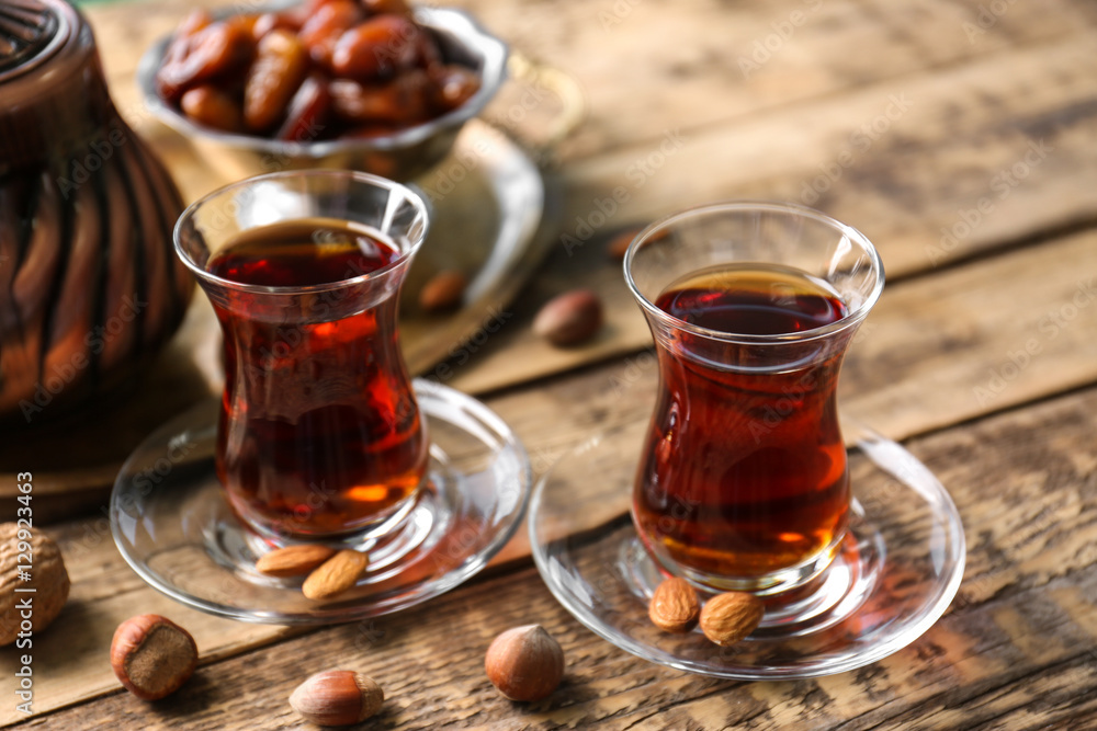 Turkish tea in traditional glasses with nuts on wooden background Turkish tea in traditional glasses with nuts on wooden background
