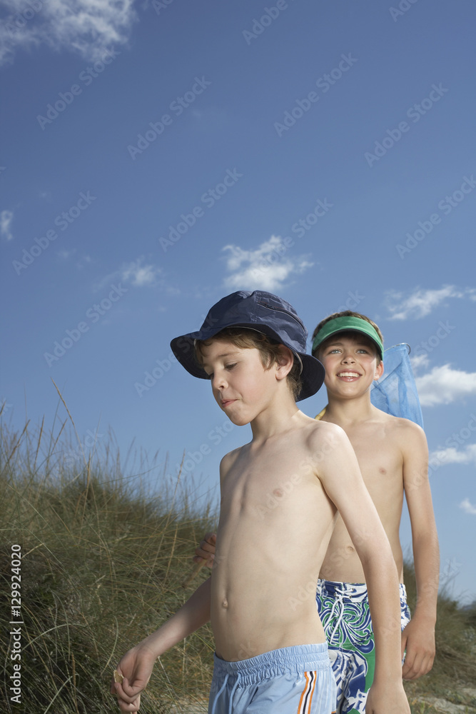 Two shirtless boys walking in beach on a sunny day Stock Photo Adobe