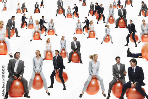 Businesspeople bouncing on inflatable balls isolated over white background