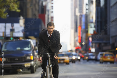 Portrait of young businessman riding bicycle to work on urban street © moodboard