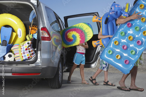 Foto Father and two children unloading beach accessories from car