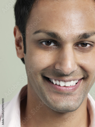 Closeup portrait of handsome young man smiling on colored background
