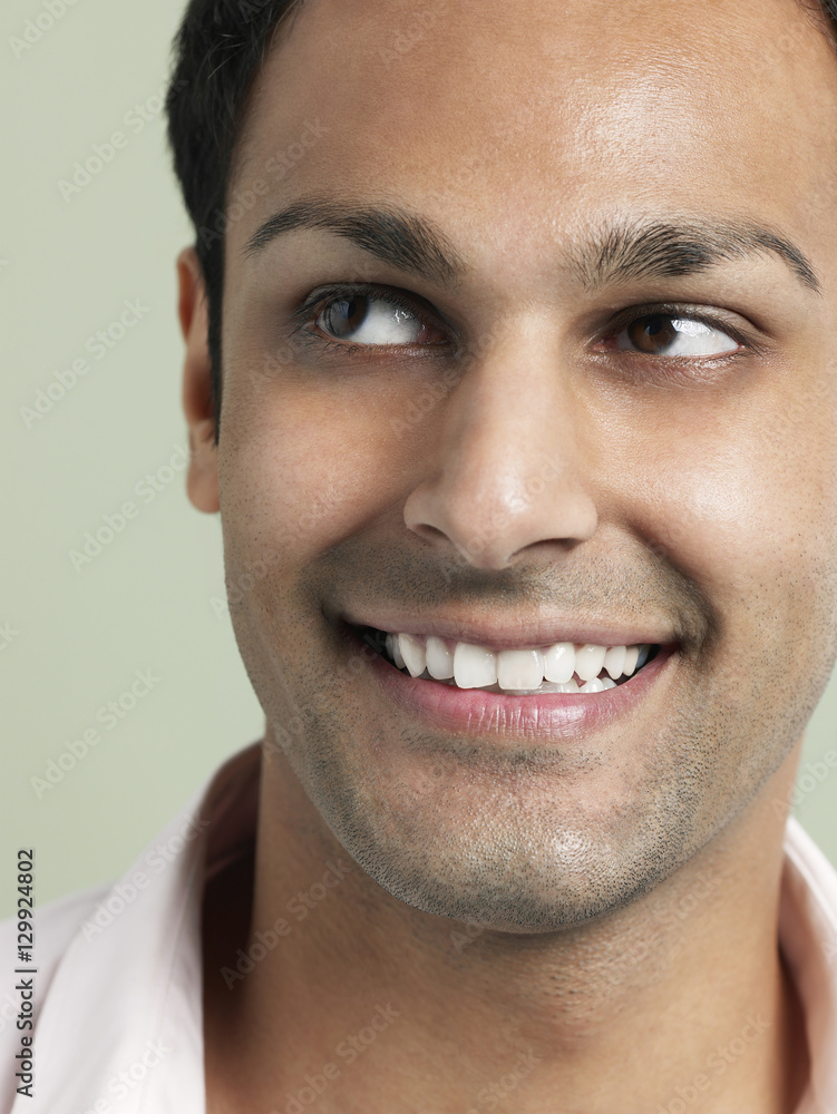 Obraz premium Closeup of young Asian man looking away and smiling on colored background