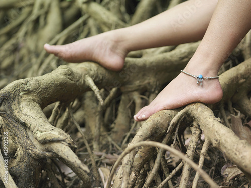 Obraz na plátně Closeup of a young woman's bare feet on roots
