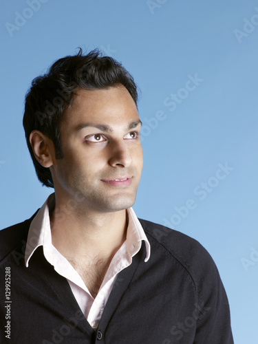 Closeup of handsome young man looking up and smiling on blue background