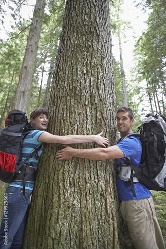 Side view portrait of a young couple hugging tree in forest © moodboard