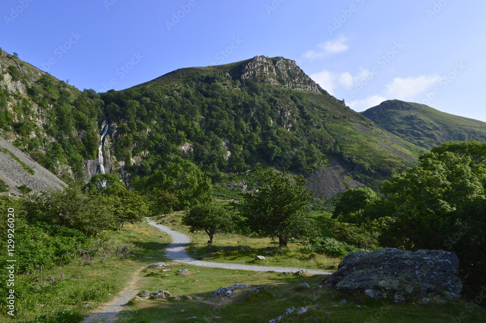 Fototapeta premium Wide landscape with Tropical waterfall and pathway leading to it on summers day, Aber falls abergwyngregyn wales