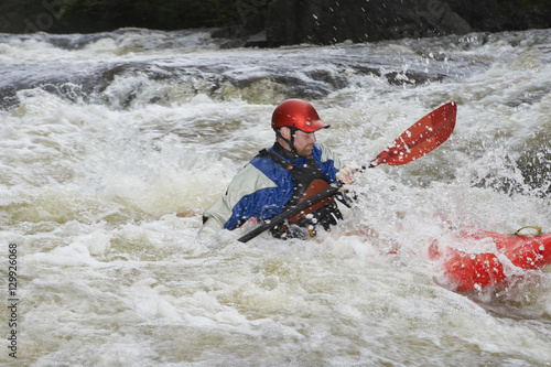 Side view of a man kayaking in rough river