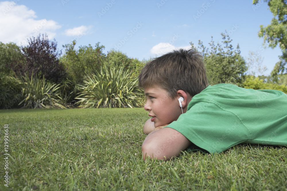 Side view of a young boy lying on grass and listening to MP3 player Stock  Photo | Adobe Stock