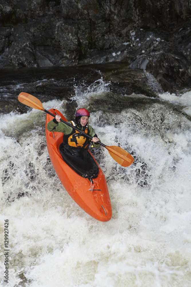 Fototapeta premium Elevated view of a woman kayaking in rough river