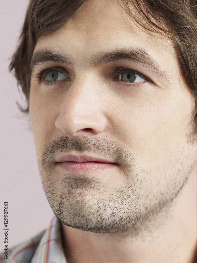 Obraz premium Closeup of thoughtful young man looking away isolated on colored background