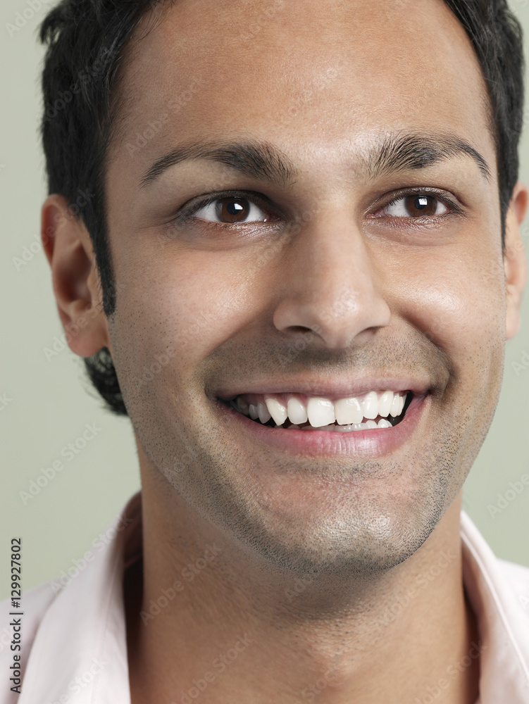 Closeup of young man looking away and smiling on colored background Closeup of young man looking away and smiling on colored background