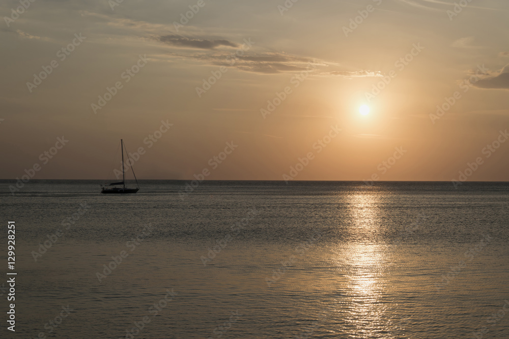 Sailboat anchored in open sea during sunset. Romantic sailing boat (yacht) picture.