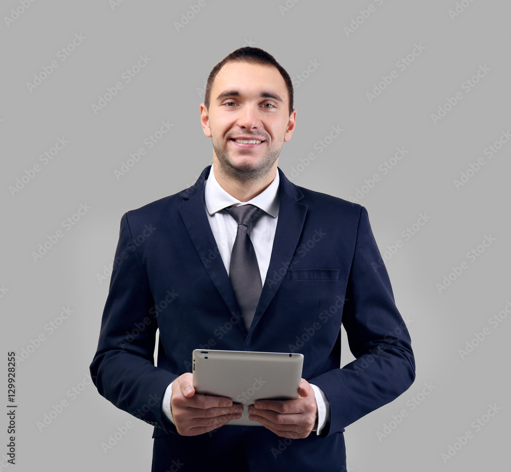 Handsome man with tablet computer on light background