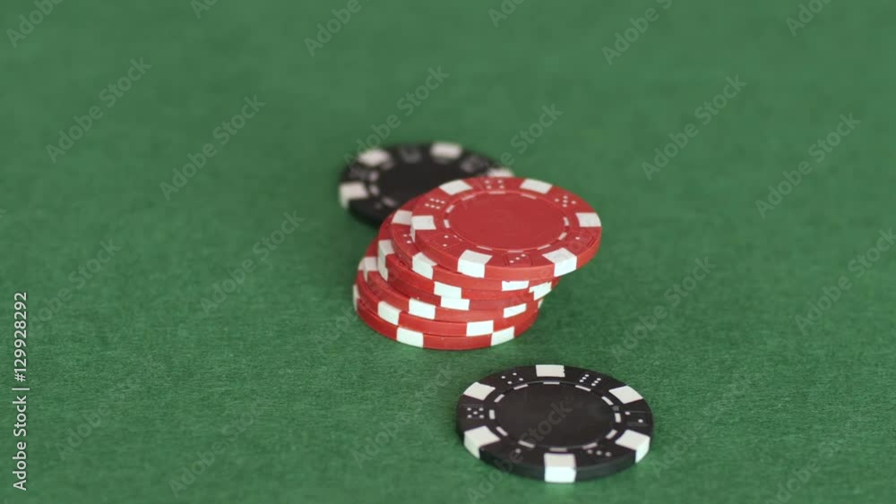 Red and black chips are on table and then other tokens are rolled towards them to form a pile, making a bet, gamble. Close up, 4K Ultra HD. Red and black chips are on table and then other tokens are rolled towards them to form a pile, making a bet, gamble. Close up, 4K Ultra HD.