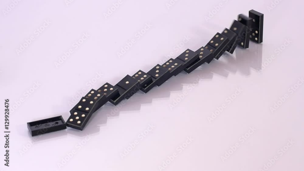Black domino blocks fall in sequence after one was knocked, concept of risk, desaster, reflective surface, games. Close up, slow motion. Black domino blocks fall in sequence after one was knocked, concept of risk, desaster, reflective surface, games. Close up, slow motion.