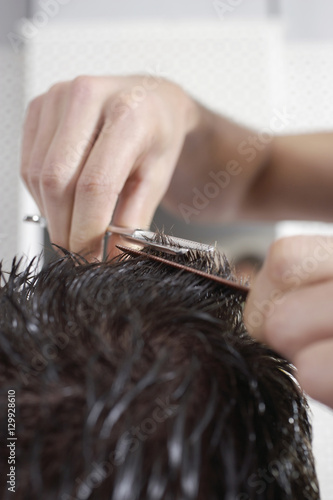 Closeup of hairdresser cutting man's hair in barbershop