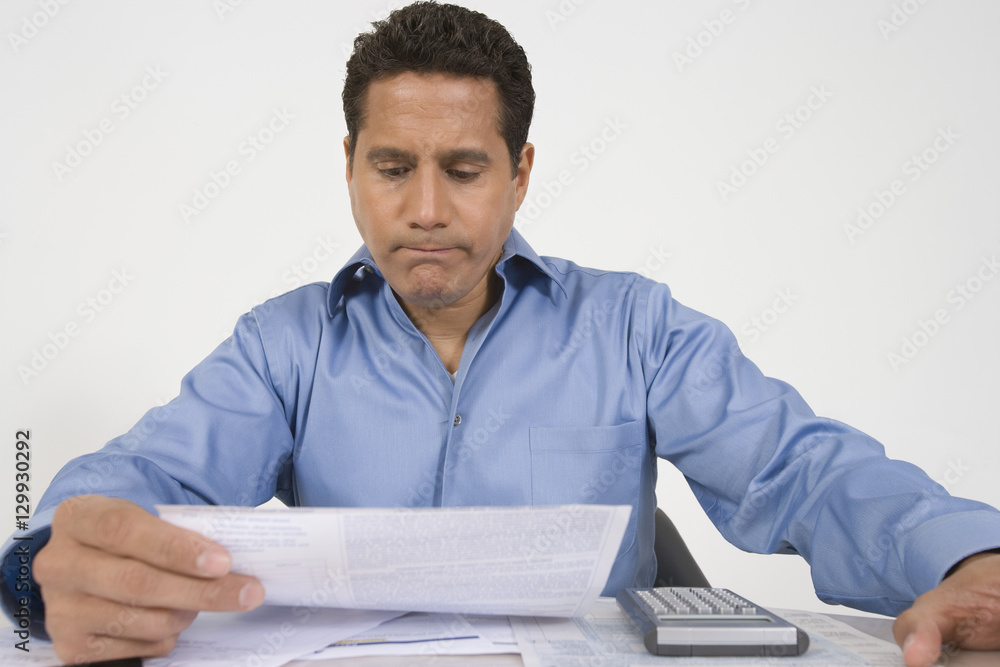 Businessman reading financial document at table Businessman reading financial document at table