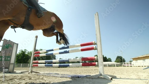 SLOW MOTION: Young competitive rider girl jumping colorful fence on horse show photo
