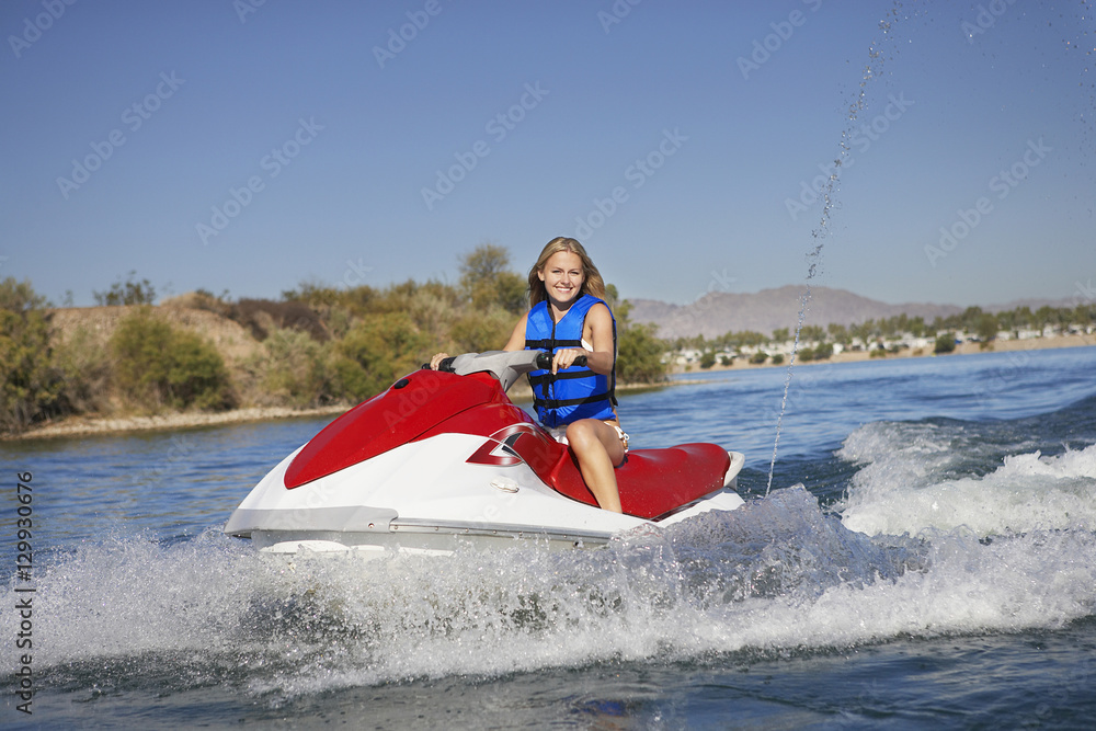 Obraz premium Portrait of happy young riding water scooter on lake
