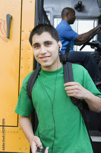 High school student listening music on MP3 player getting off school bus