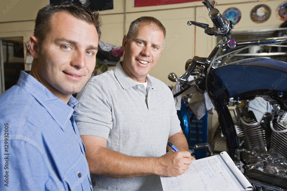 Portrait of a male mechanics working together at motorcycle workshop Portrait of a male mechanics working together at motorcycle workshop