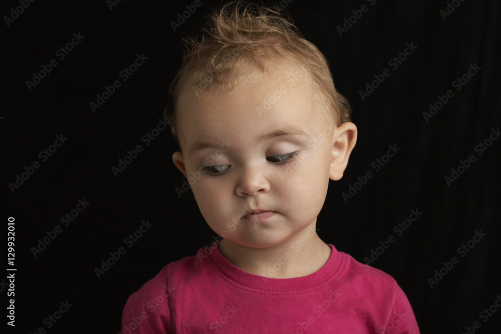 Closeup of cute baby boy looking down against black background Closeup of cute baby boy looking down against black background