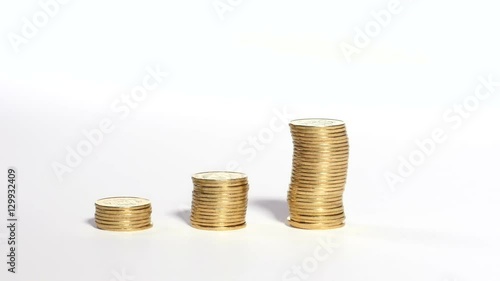 Three piles of golden coins on white background, male hand adds few more on top of one pile, finances, business, carculating money, saving. Close up, 4K Ultra HD.