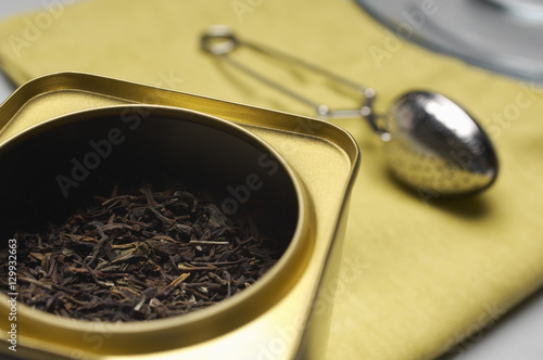 Closeup of tea leaves in a container with strainer on napkin