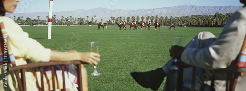 Foto Midsection of couple holding champagne flutes while watching polo match