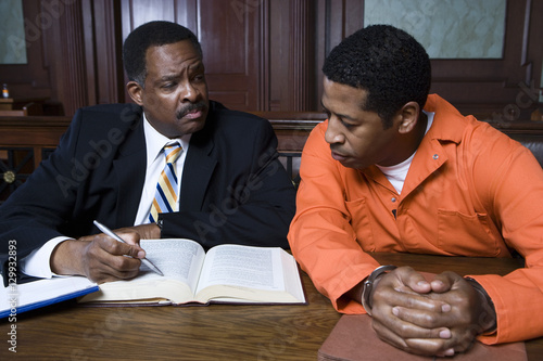 Male lawyer sitting with criminal in the courtroom photo