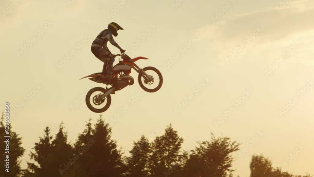 SLOW MOTION: Pro freestyle motocross biker jumping extreme trick over sunset sky SLOW MOTION: Pro freestyle motocross biker jumping extreme trick over sunset sky