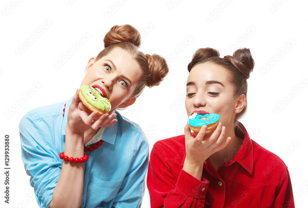Funny young women eating tasty donuts on white background Funny young women eating tasty donuts on white background