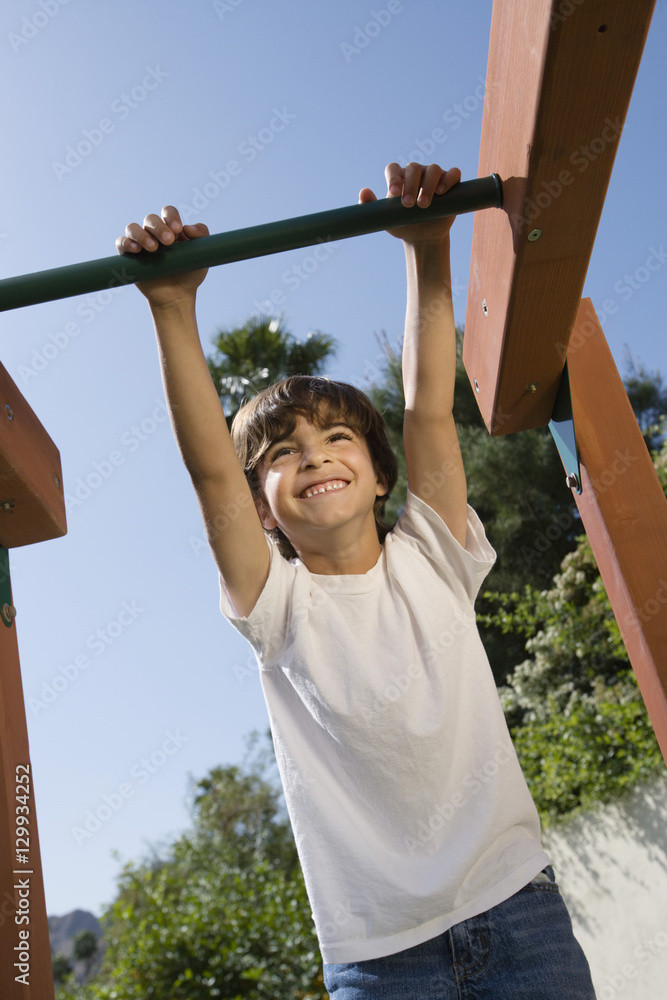 Fototapeta premium Happy boy swaying on a jungle gym