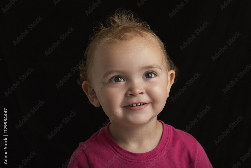Closeup of smiling baby boy looking away against black background Closeup of smiling baby boy looking away against black background