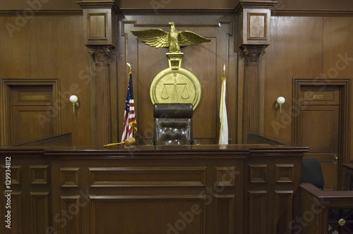 Legal scales with flags behind judge's chair in courtroom
