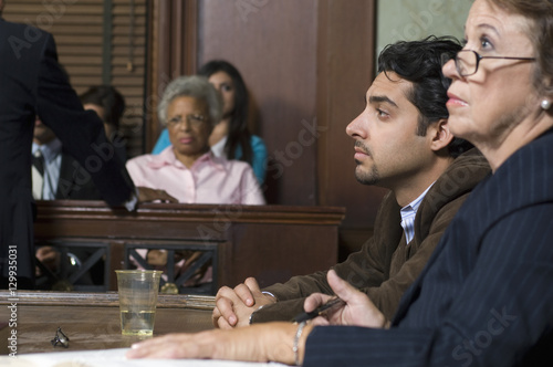 Defense lawyer sitting with client during prosecution in courthouse photo