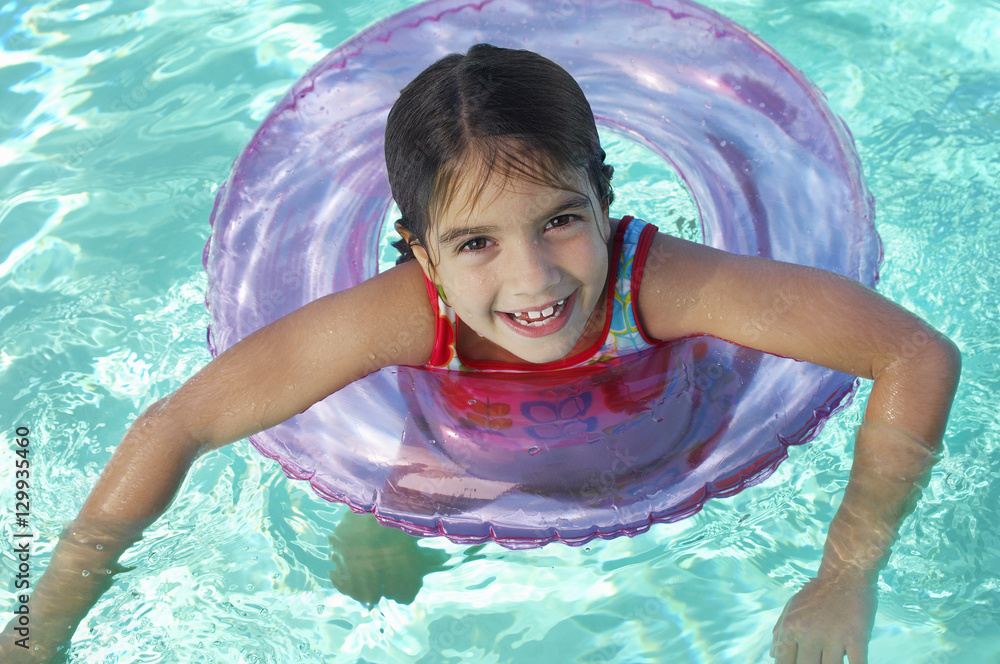Happy cute little elementary girl floating on inflatable raft in ...