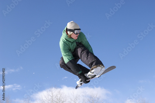 Low angle view of male snowboarder performing stunt against blue sky
