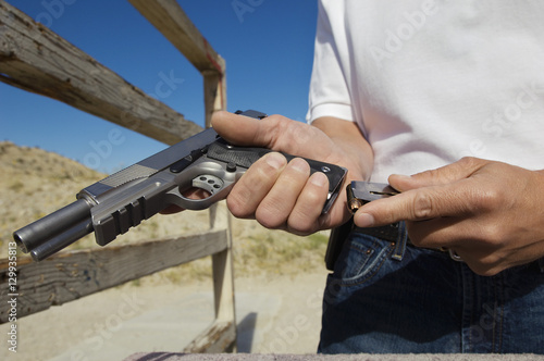 Closeup of a man loading magazine into gun at firing range