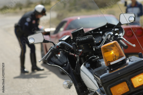 Closeup of motorcycle with traffic cop and car in background