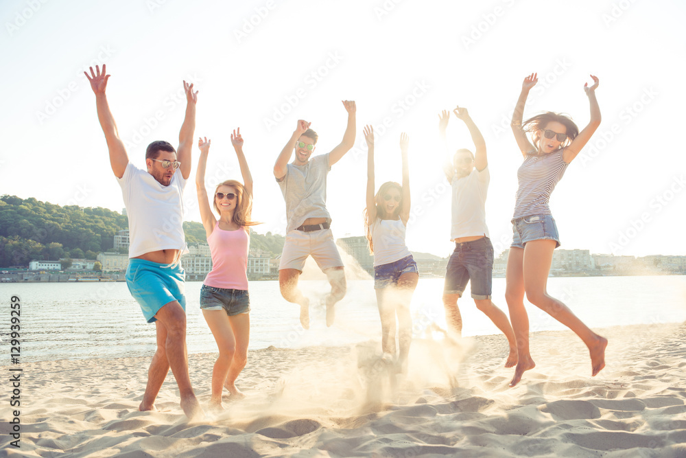 Young friends enjoying beach party and jumping on summer sunset Young friends enjoying beach party and jumping on summer sunset