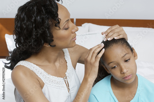 An African American woman examining sick daughter at home