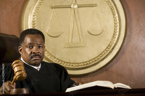 Portrait of a male judge holding wooden gavel in courtroom