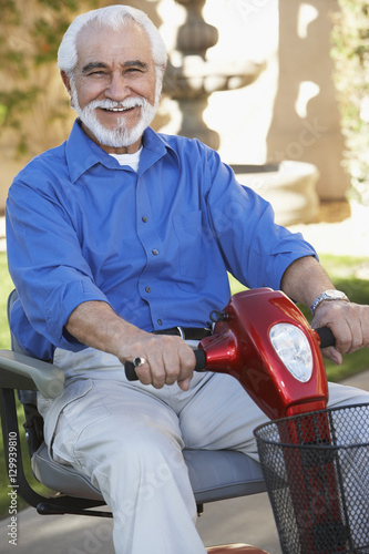 Canvas Print Portrait of a cheerful senior man on motor scooter