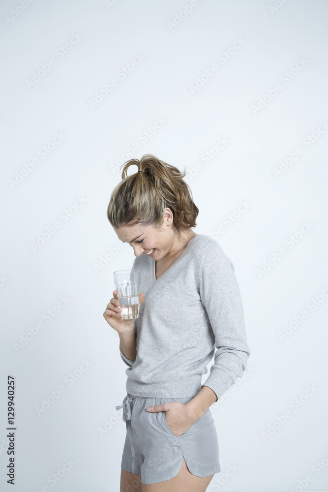 Beautiful young woman holding glass of water isolated over colored background Beautiful young woman holding glass of water isolated over colored background