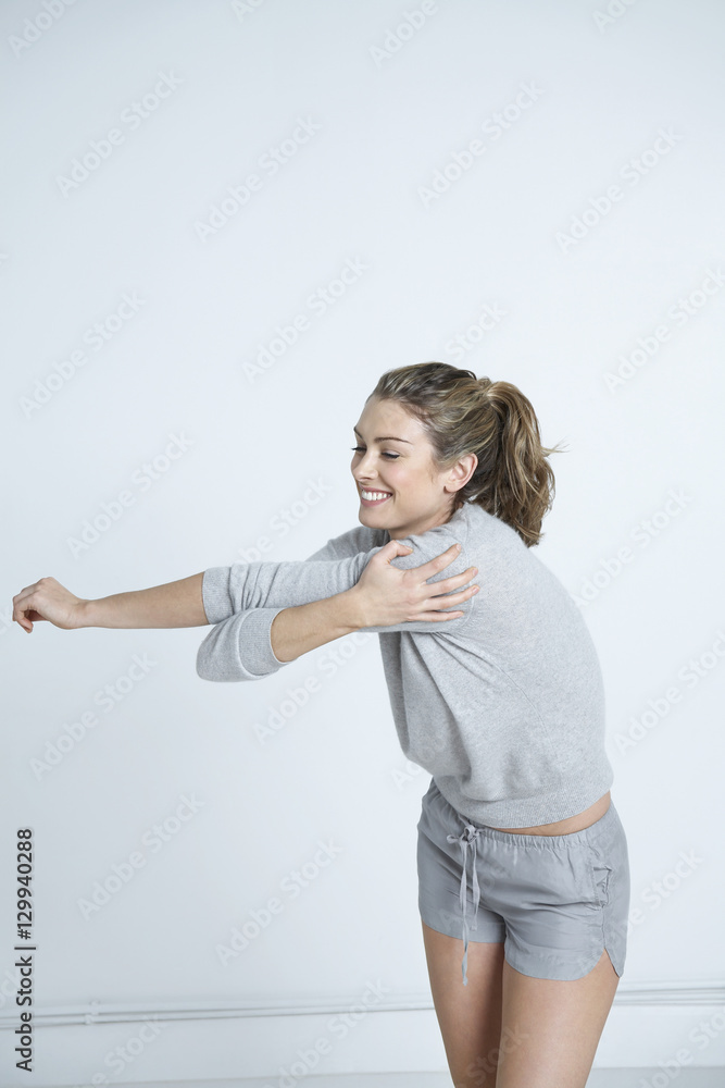 Happy young woman stretching hand in house